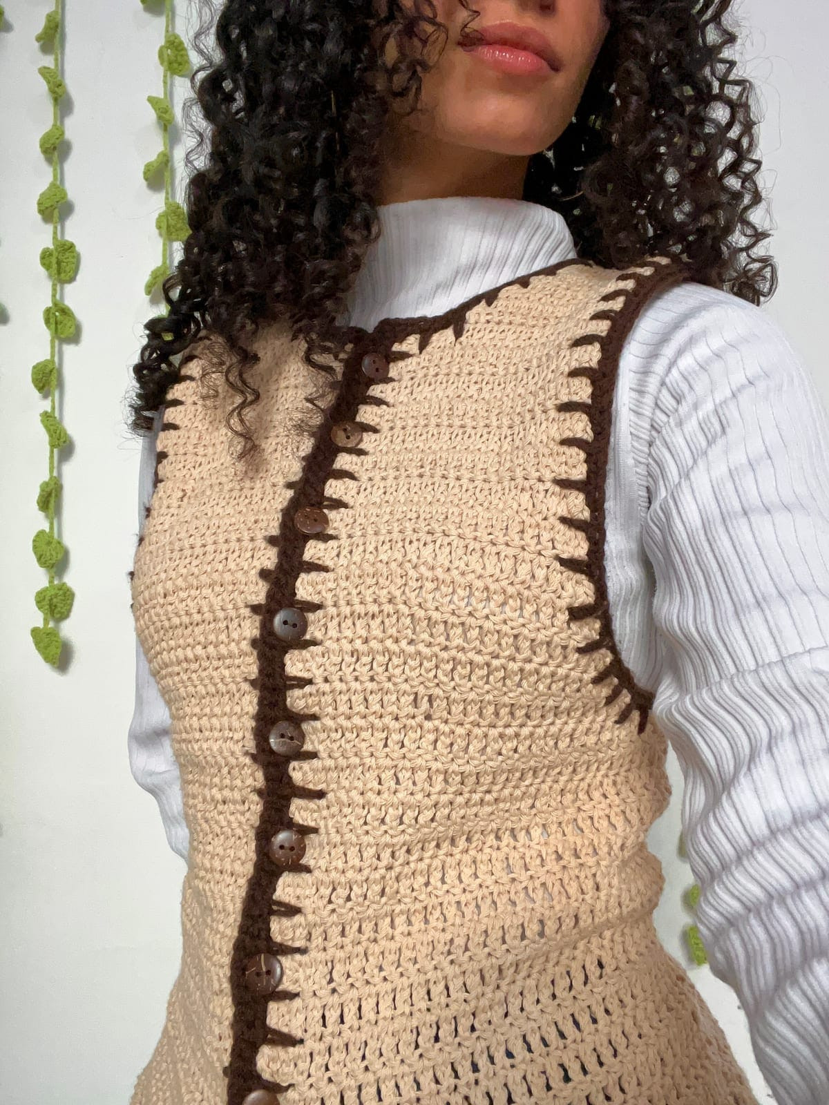 Chaleco tejido a crochet con botones y borde marrón, puesto sobre una polera blanca