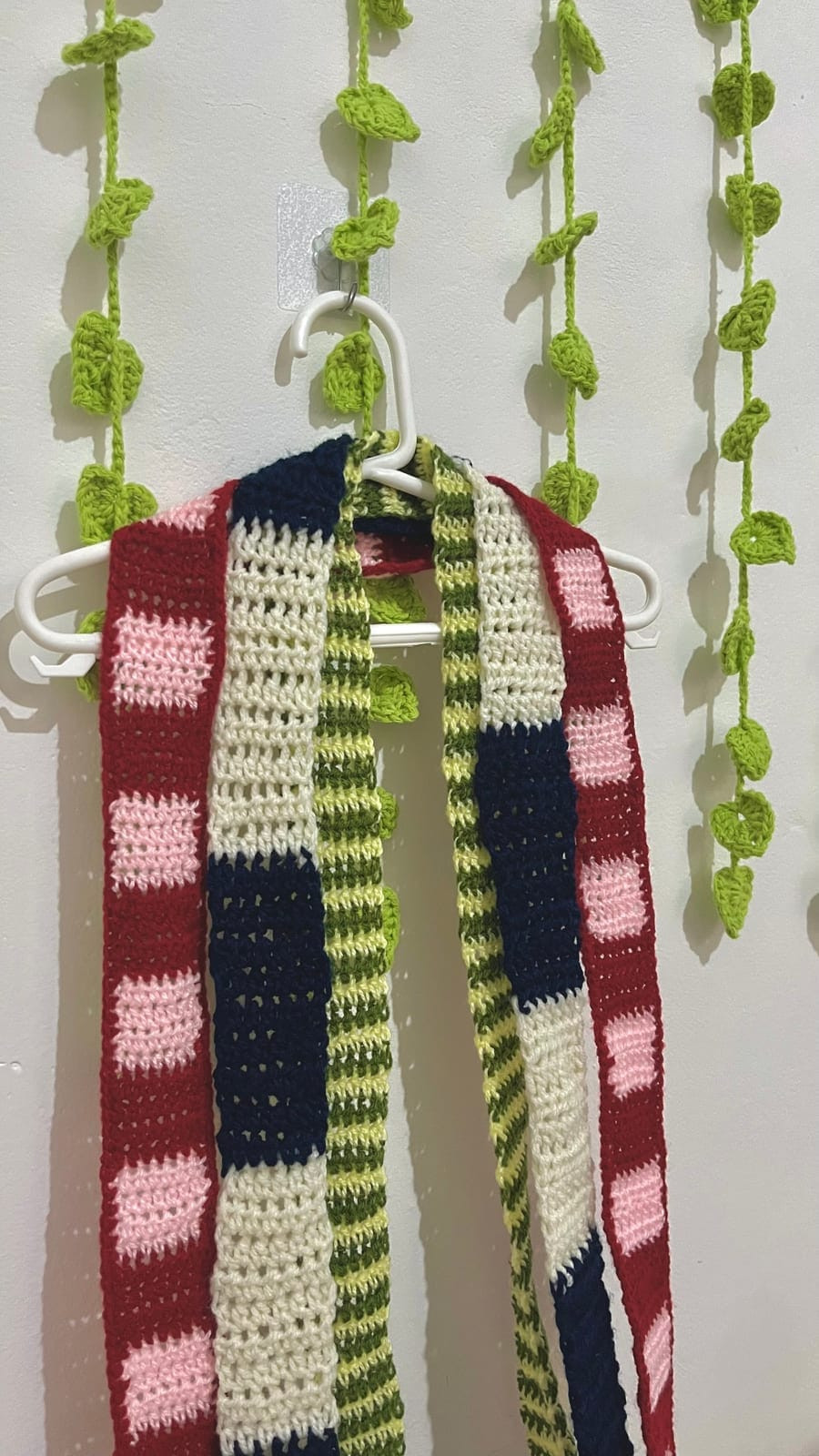 Mini bufandas tejidas a crochet en colores, colgadas en una percha